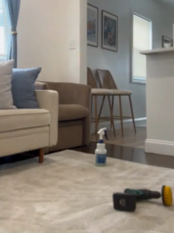 Area rug being scrubbed with a drill brush inside a home during an in-home rug cleaning